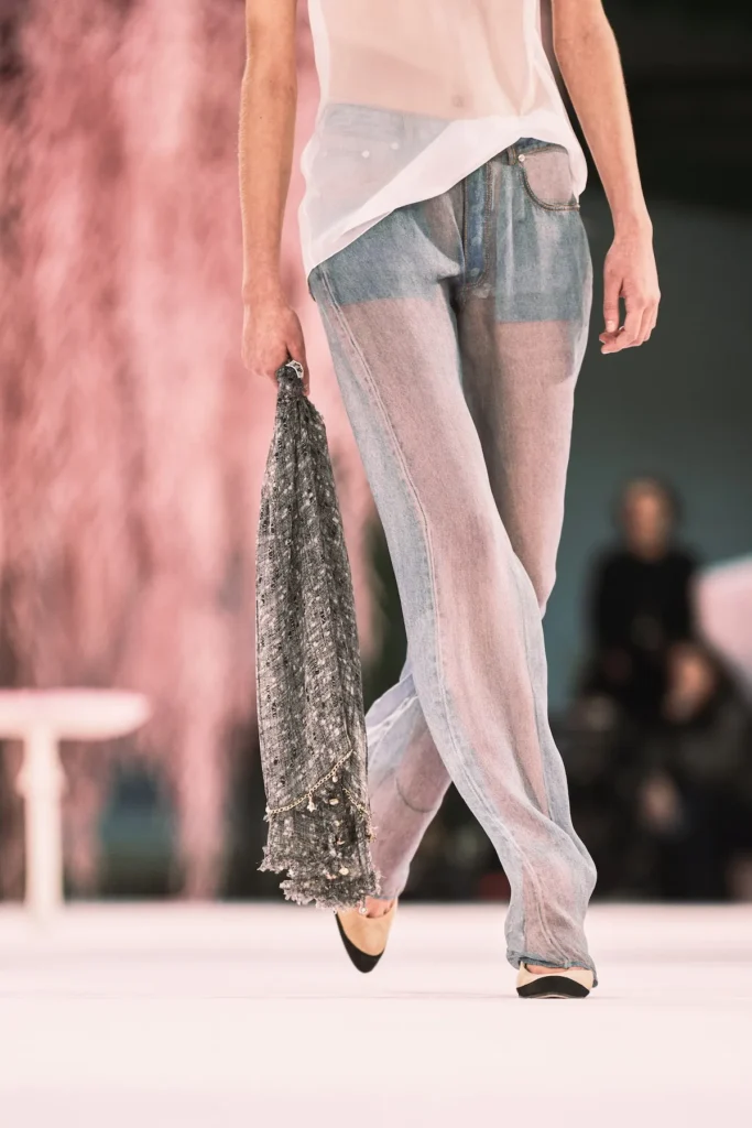 Fotografia z prehliadky Chanel SS 2026 v Paríži, kde Matthieu Blazy debutoval ako kreatívny riaditeľ. Modelky prezentujú tweedové kostýmy, pastelové scenérie a surrealistické prvky inšpirované literatúrou a popkultúrou.
