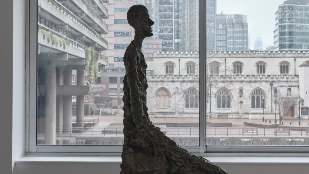 Alberto Giacometti socha elongovaná ľudská postava okno Barbican Londýn výstava 2026 Lynda Benglis