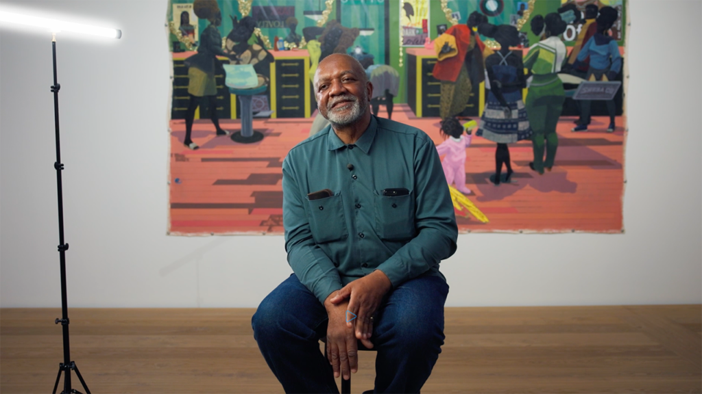 Kerry James Marshall sedí pred veľkoformátovou farebnou maľbou zobrazujúcou čierne postavy v interiéri, galéria, 2026
