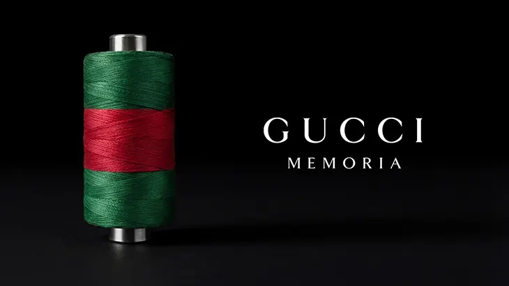 Vizuál výstavy Gucci Memoria — cievka so zelenou a červenou niťou na čiernom pozadí s nápisom Gucci Memoria.