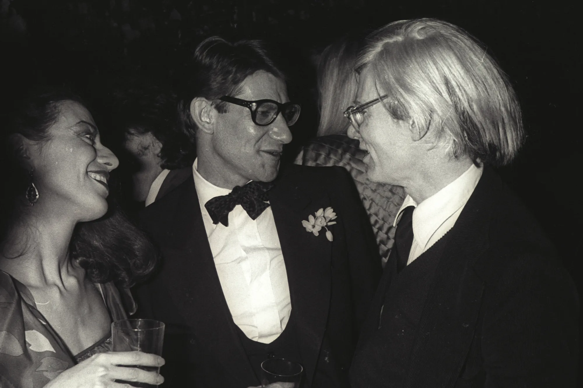 Saint Laurent Warhol — Yves Saint Laurent a Andy Warhol na párty v Paríži 1979, čiernobiela fotografia, v pozadí Warholov portrét Saint Laurenta 1972.