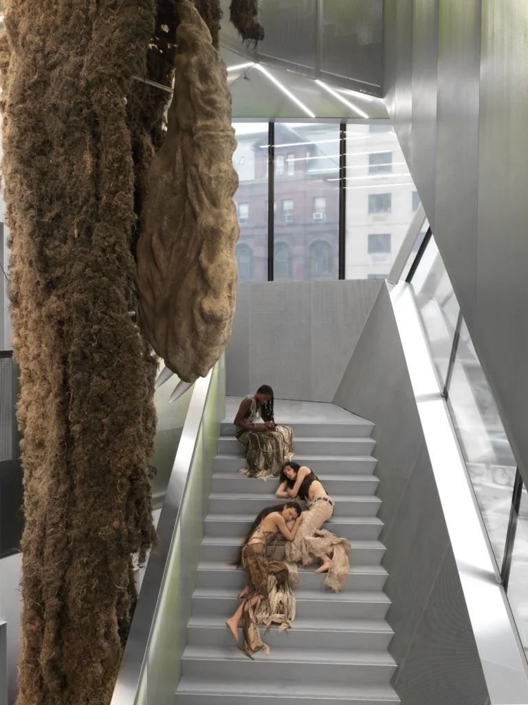 New Museum 2026, Klára Hosnedlová, Shelter, 2026 — monumentálna organická socha z ľanu a kameňa v atriovej schodnici New Museum, s performermi v popredí.