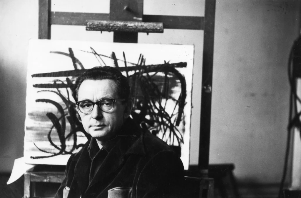 Hans Hartung pri práci vo svojom ateliéri, čiernobiela fotografia z roku 1958.