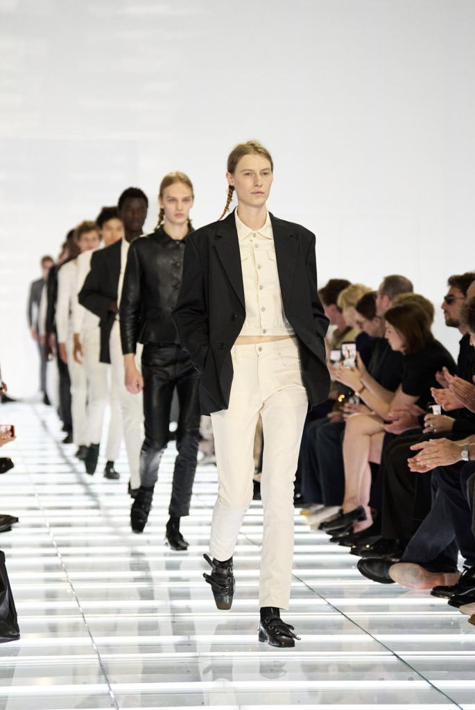 Prada Spring 2027 menswear, model v krémových džínsoch a čiernom saku