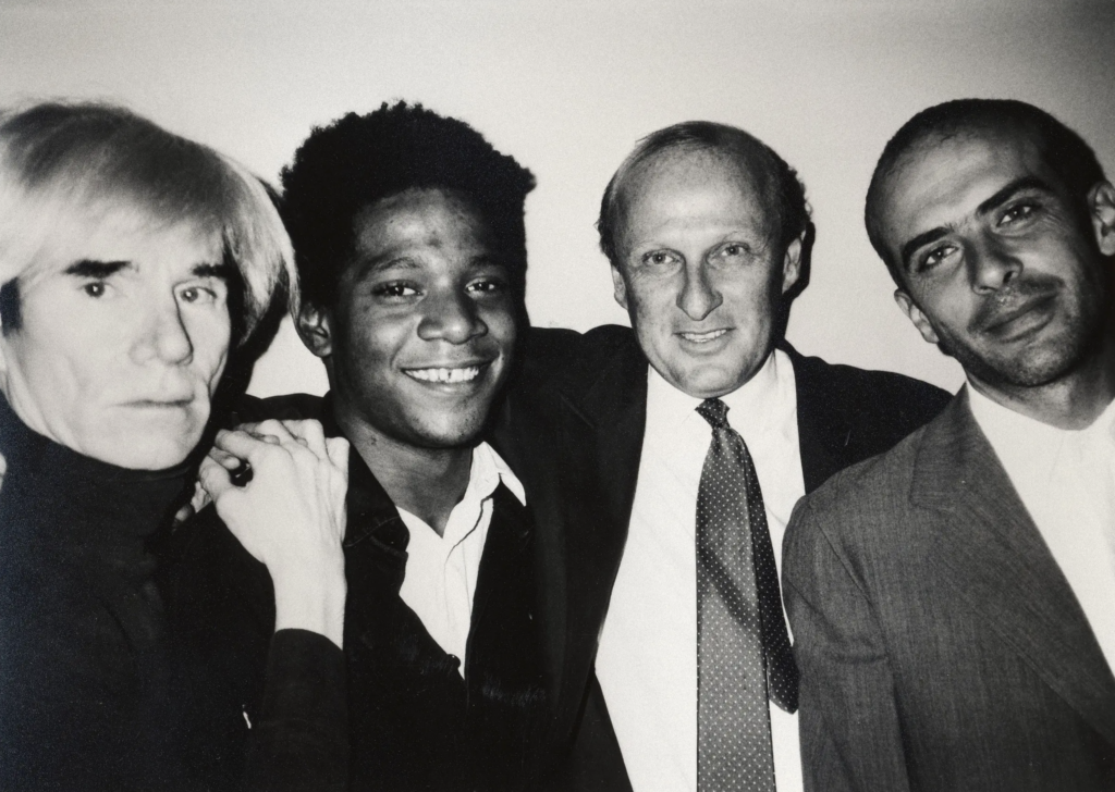 Andy Warhol, Jean-Michel Basquiat, Bruno Bischofberger a Francesco Clemente spolu na čiernobielej archívnej fotografii v roku 1984