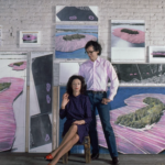 Christo a Jeanne-Claude sedia v ateliéri obklopení prípravnými kresbami a kolážami projektu Surrounded Islands s ružovými ostrovmi na modrej vode
