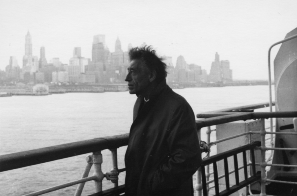Čiernobiela archívna fotografia Alberta Giacomettiho na streche budovy v New Yorku v roku 1965, v pozadí panoráma mesta