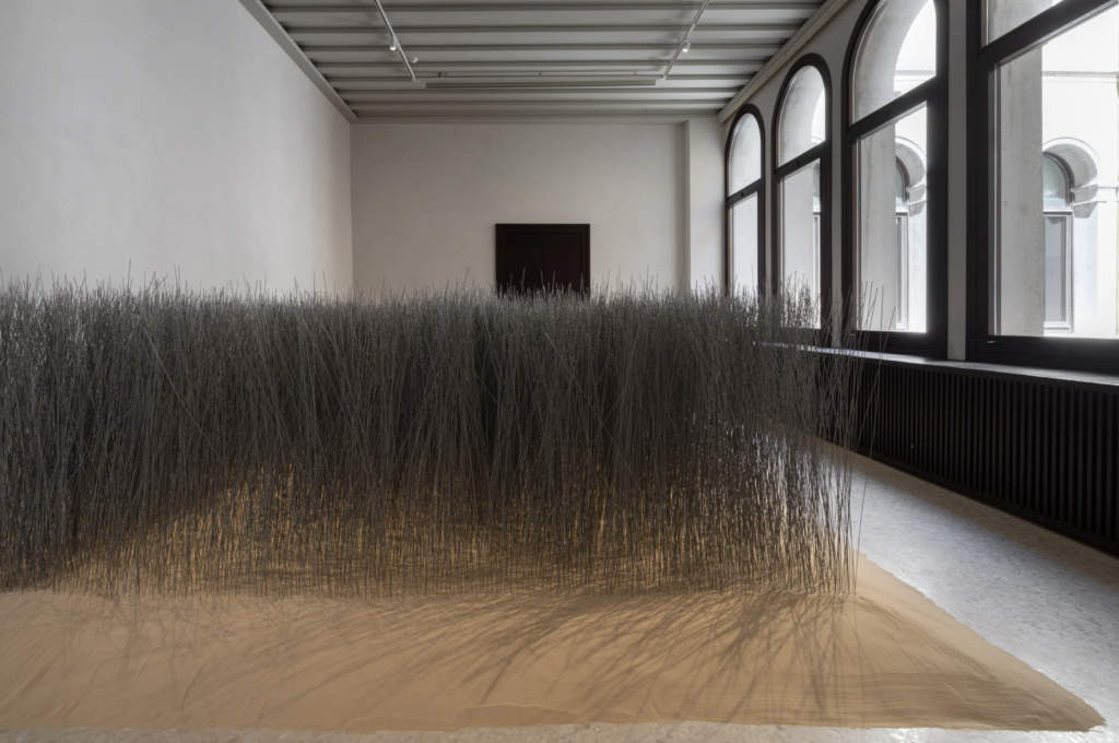 Inštalácia Lee Ufana Relatum Iron Field v San Marco Art Centre v Benátkach, stovky oceľových tyčí zapichnutých v piesku vypĺňajú celú sálu s klenutými oknami