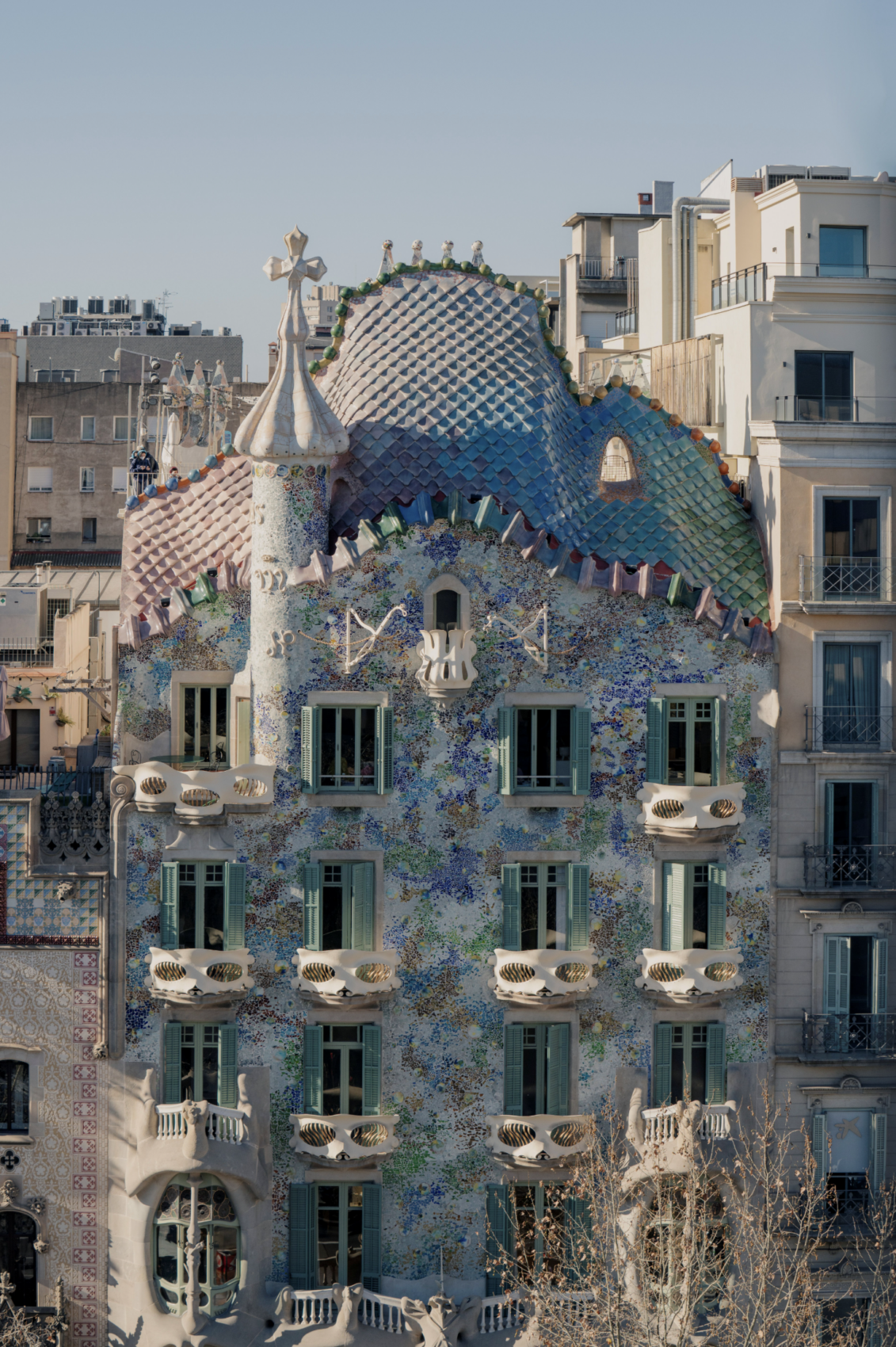 Fasáda Casa Batlló v Barcelone s vlnitou strechou pripomínajúcou dračí chrbát, mozaikovým obkladom v odtieňoch modrej a zelenej a balkónmi v tvare masiek