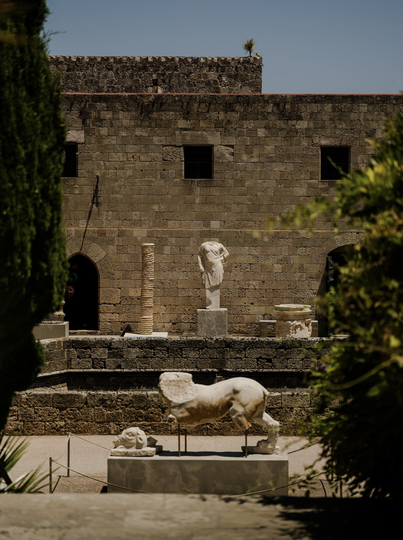 Terakotový stĺp od Davida Scanavina s povrchom pripomínajúcim previazané lano, stojaci v záhrade Archeologického múzea Rodosu medzi antickými sochami a ruinami