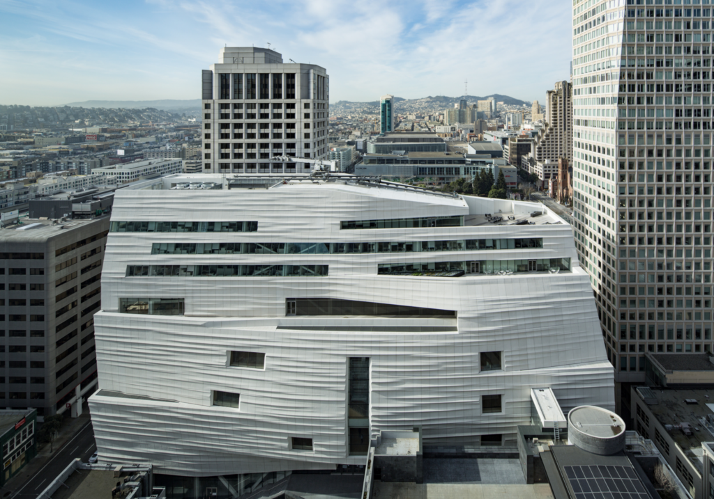 Rozšírenie SFMOMA od Snøhetty so zvlnenou bielou fasádou pripomínajúcou hmlu, obklopené mrakodrapmi San Francisca