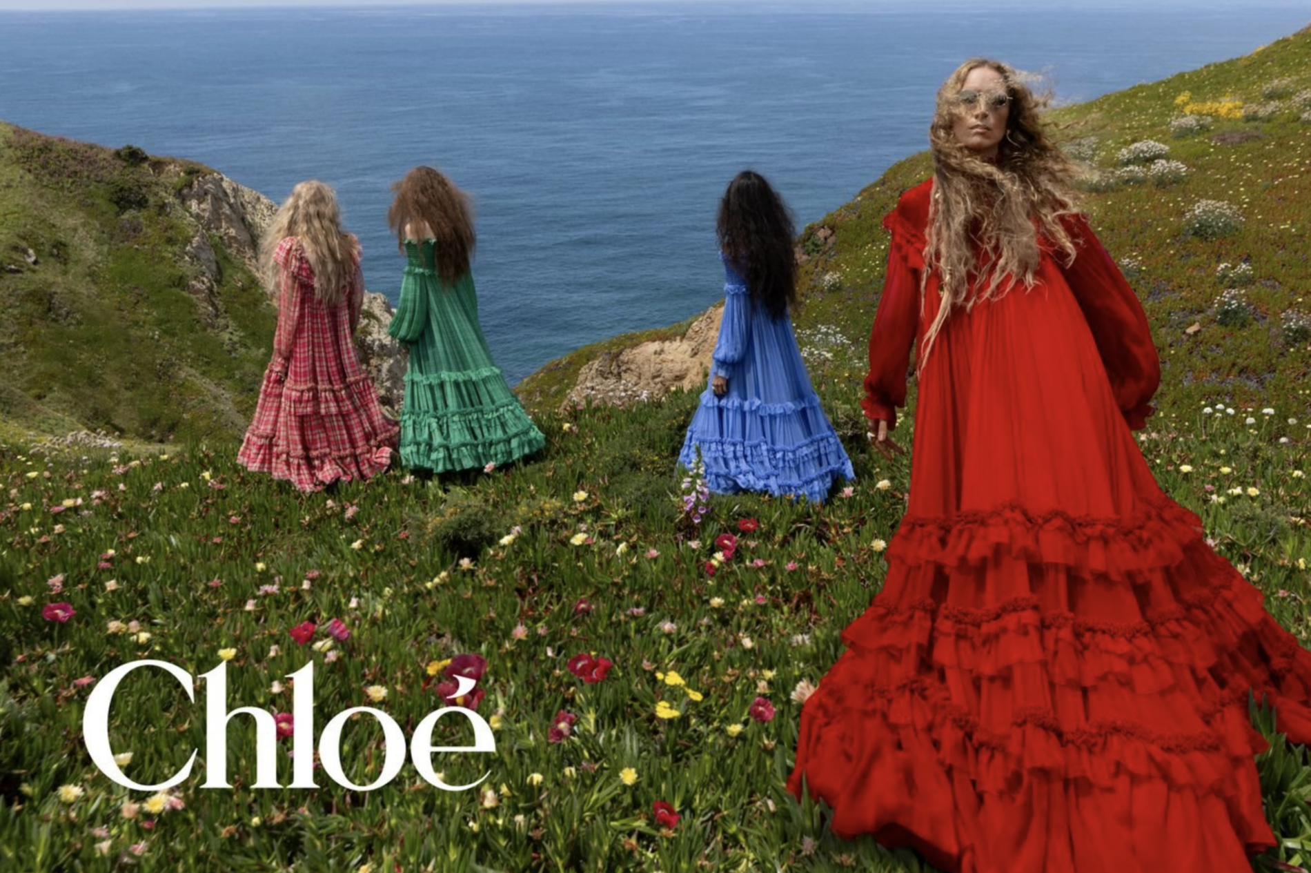 Modelky vo farebných šatách Chloé stojace na útese s výhľadom na more