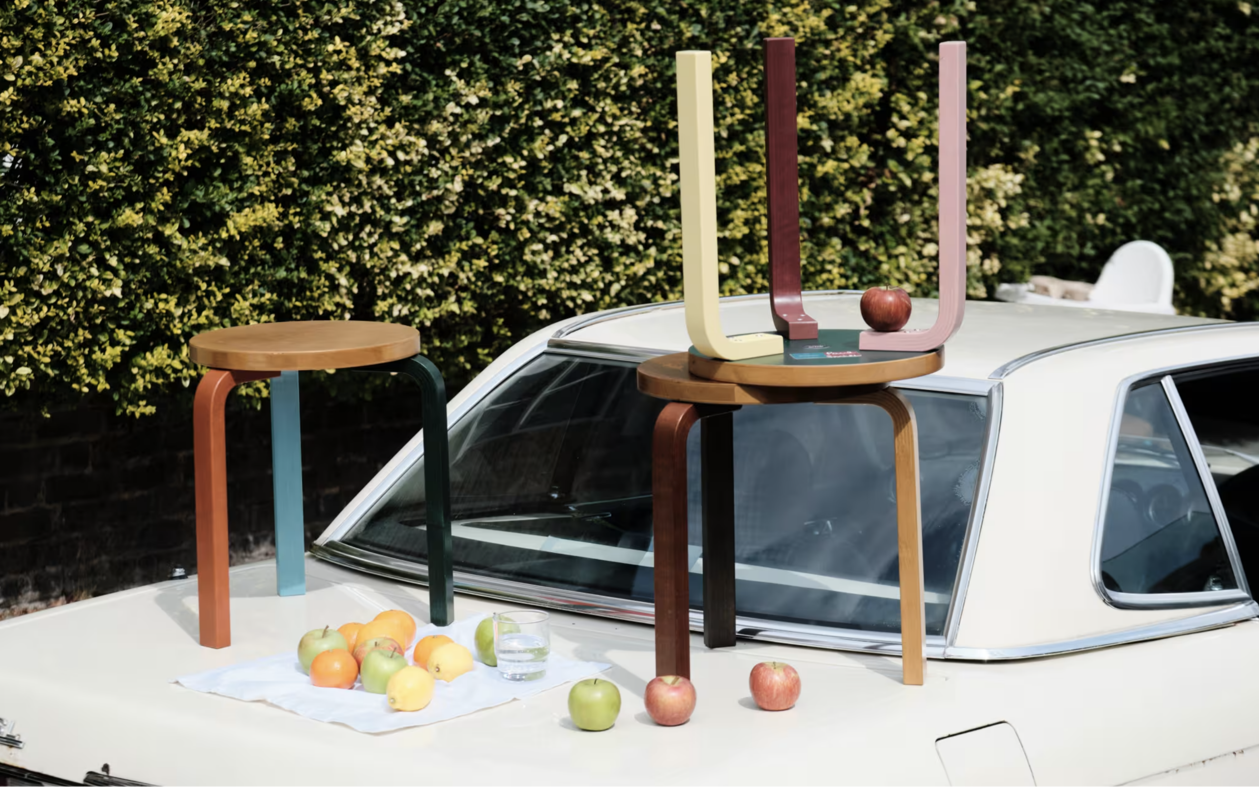 Stoličky 60 od Artek Reimagined by Paul Smith s farebnými nohami umiestnené na streche auta v exteriéri