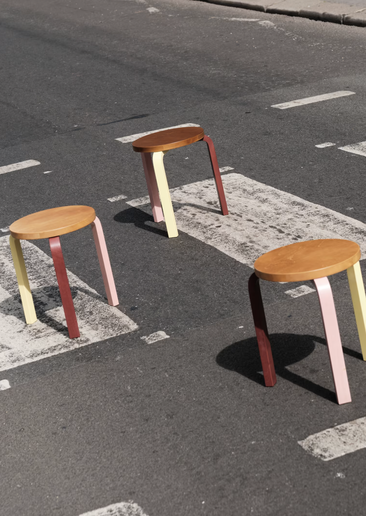 Tri stoličky Artek Reimagined by Paul Smith s farebnými nohami umiestnené na priechode pre chodcov