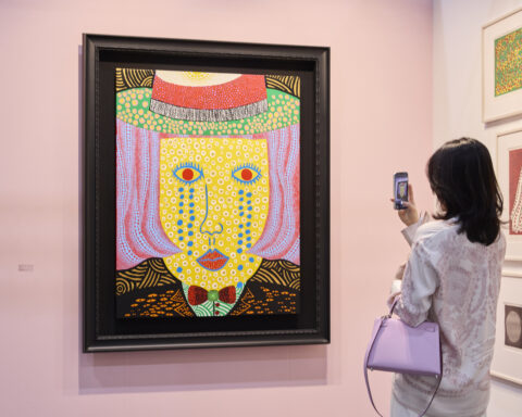 Návštevníčka si prezerá farebnú pop-artovú maľbu na stánku Ota Fine Arts na Frieze Seoul