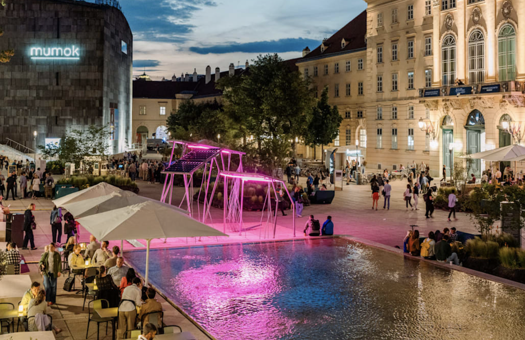 Nočný pohľad na Museumsquartier vo Viedni s budovou mumok a ružovo osvetleným jazierkom