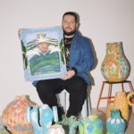 José Campos, Studio Lenca, drží maľovaný portrét obklopený farebnými keramickými nádobami